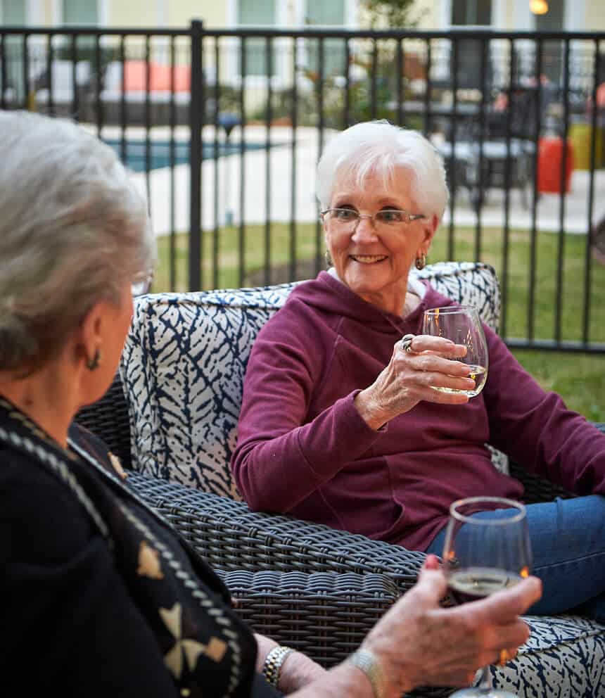 2 ladies sitting outside on the patio enjoying a glass of wine