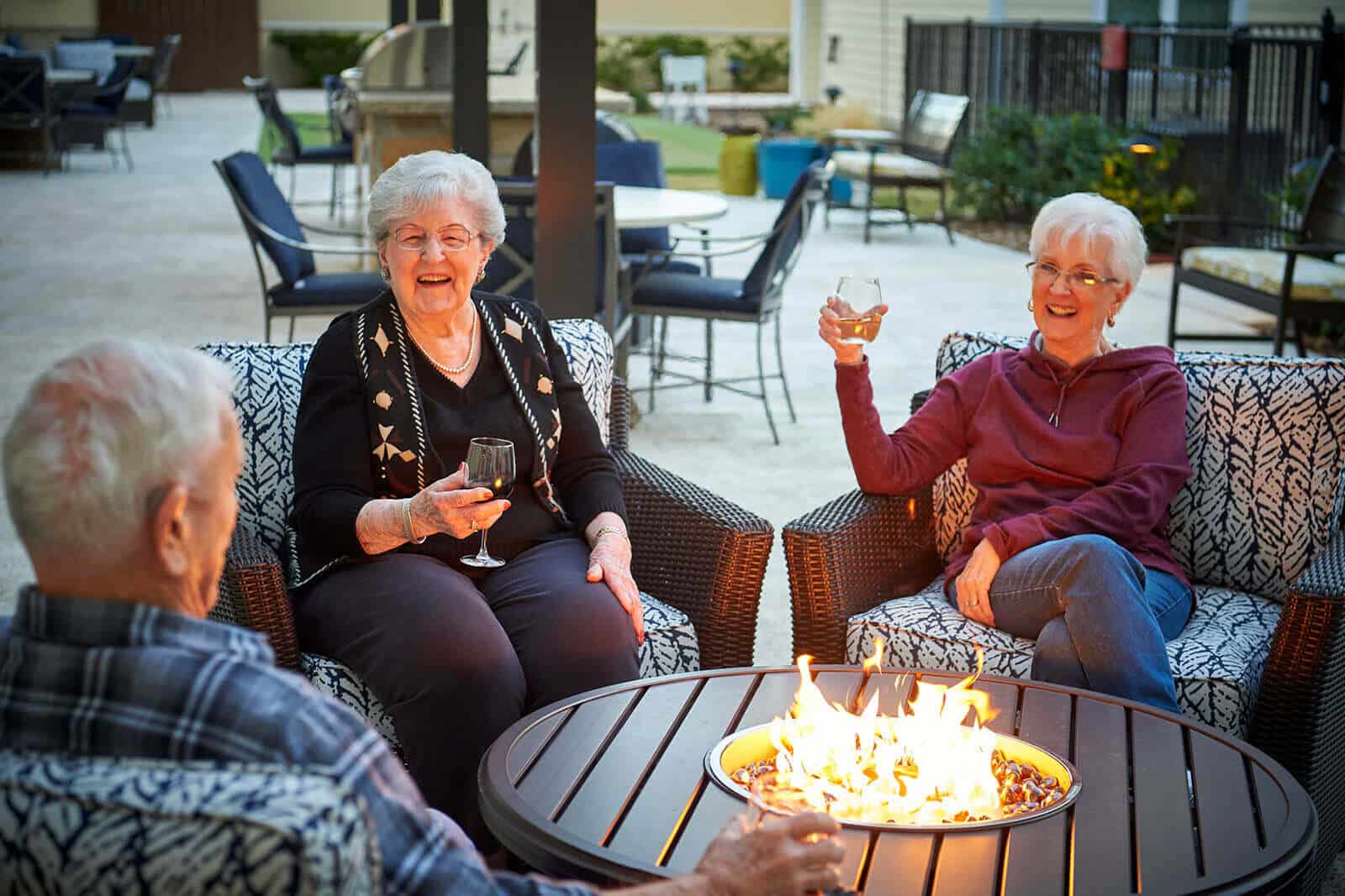 residents laughing and sipping wine by the fire